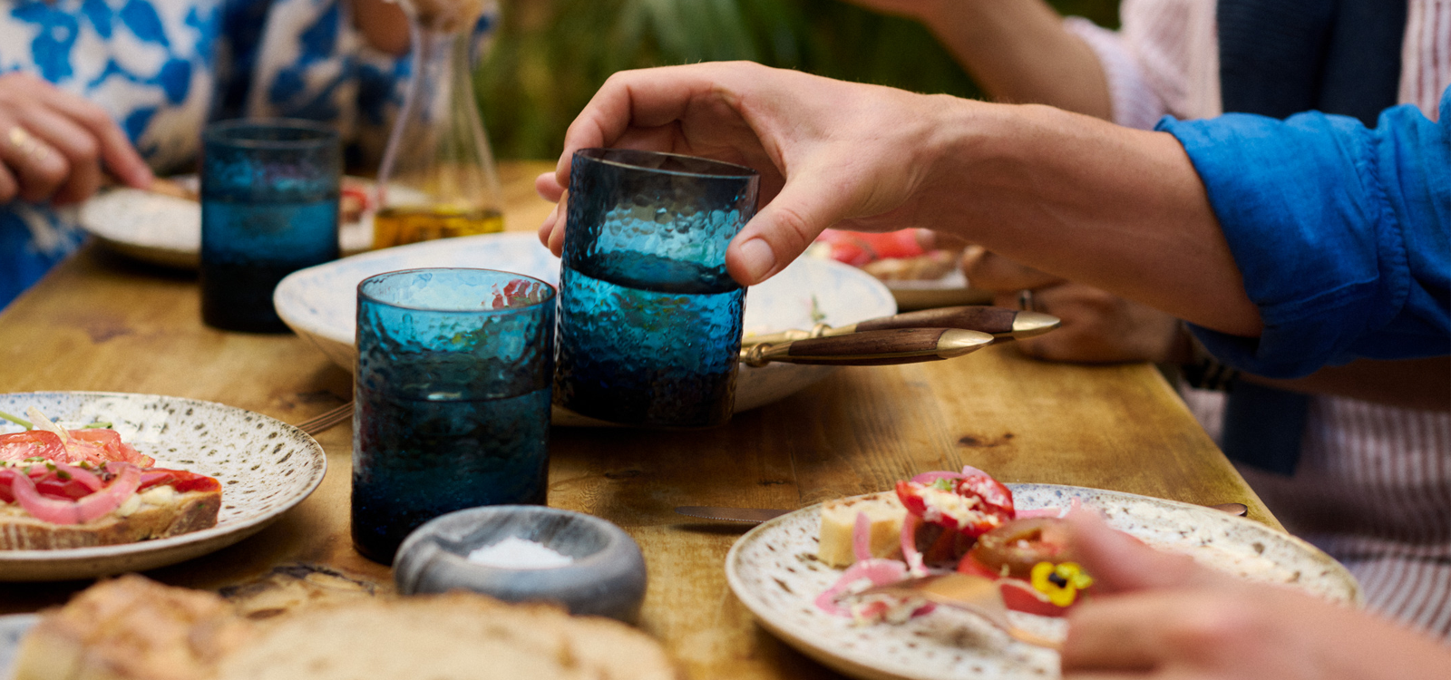 Hand holding a glass at a dinner table