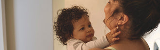Smiling mother holding her baby closely, highlighting the emotional and physical journey of postpartum recovery.