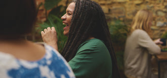 Woman laughing in a social setting, representing confidence and relief from managing overactive bladder symptoms.