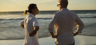 A man and woman talk on a beach