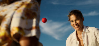 Woman smiling while playing catch outdoors with another person during sunset—illustrating the importance of staying active during menopause.
