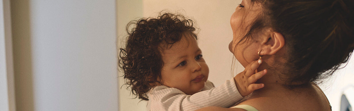 Smiling mother holding her baby closely, highlighting the emotional and physical journey of postpartum recovery.