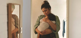 Mother gently holding her baby in a softly lit room, illustrating a moment of care in an article about frequent urination during pregnancy and related tips