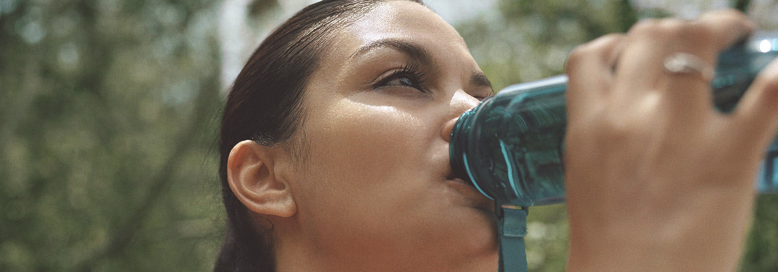 Close-up of a woman drinking water outdoors, symbolising hydration and its link to urinary health and polyuria.