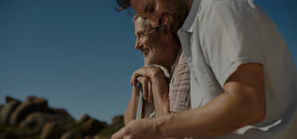 An older man and younger man sit together and talk