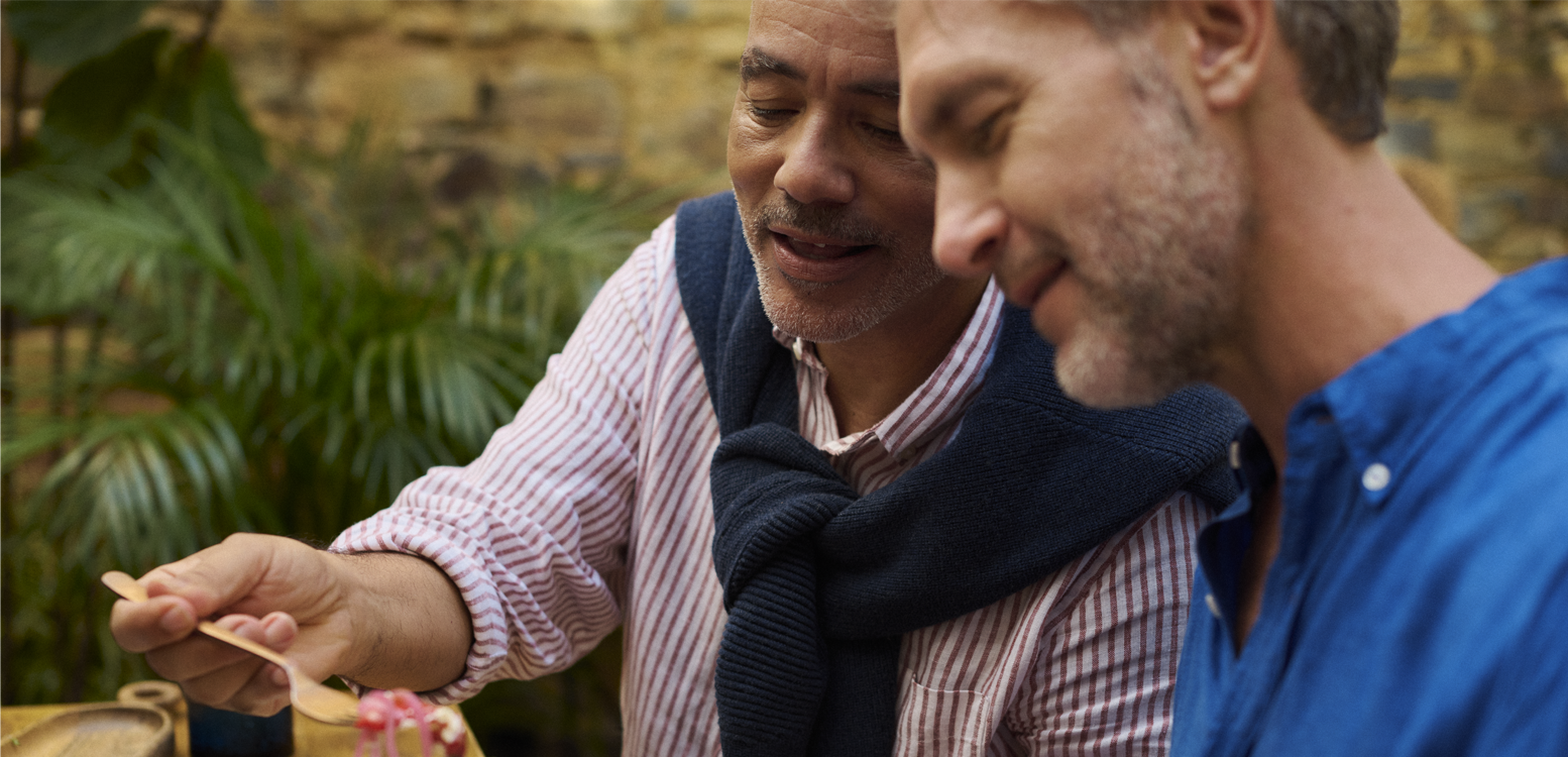 Two men enjoying a meal together outdoors, representing support and quality of life after prostate surgery in an article about incontinence management.